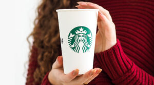 Person holding a Starbucks branded coffee cup